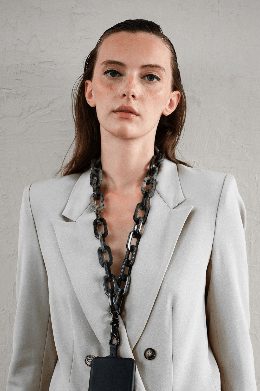 Model wearing the SPECSET STATELY Chunky Gray Tortoise Phone Chain as a lanyard/necklace over a light blazer.