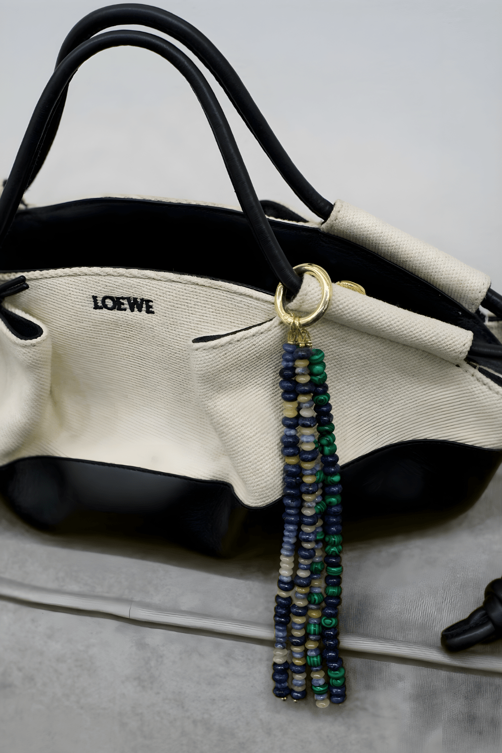 Stone Drop Multi-Gemstone Tassel Charm clipped to a purse handle, showcasing its size and texture as a versatile Handbag Accessory.