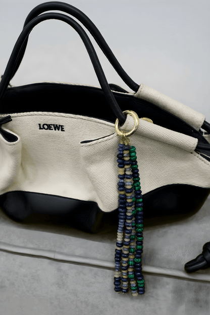 Stone Drop Multi-Gemstone Tassel Charm clipped to a purse handle, showcasing its size and texture as a versatile Handbag Accessory.