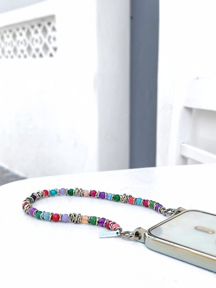 SPECSET Tropic Tones multicolor gemstone phone strap attached to a phone case on a white table.