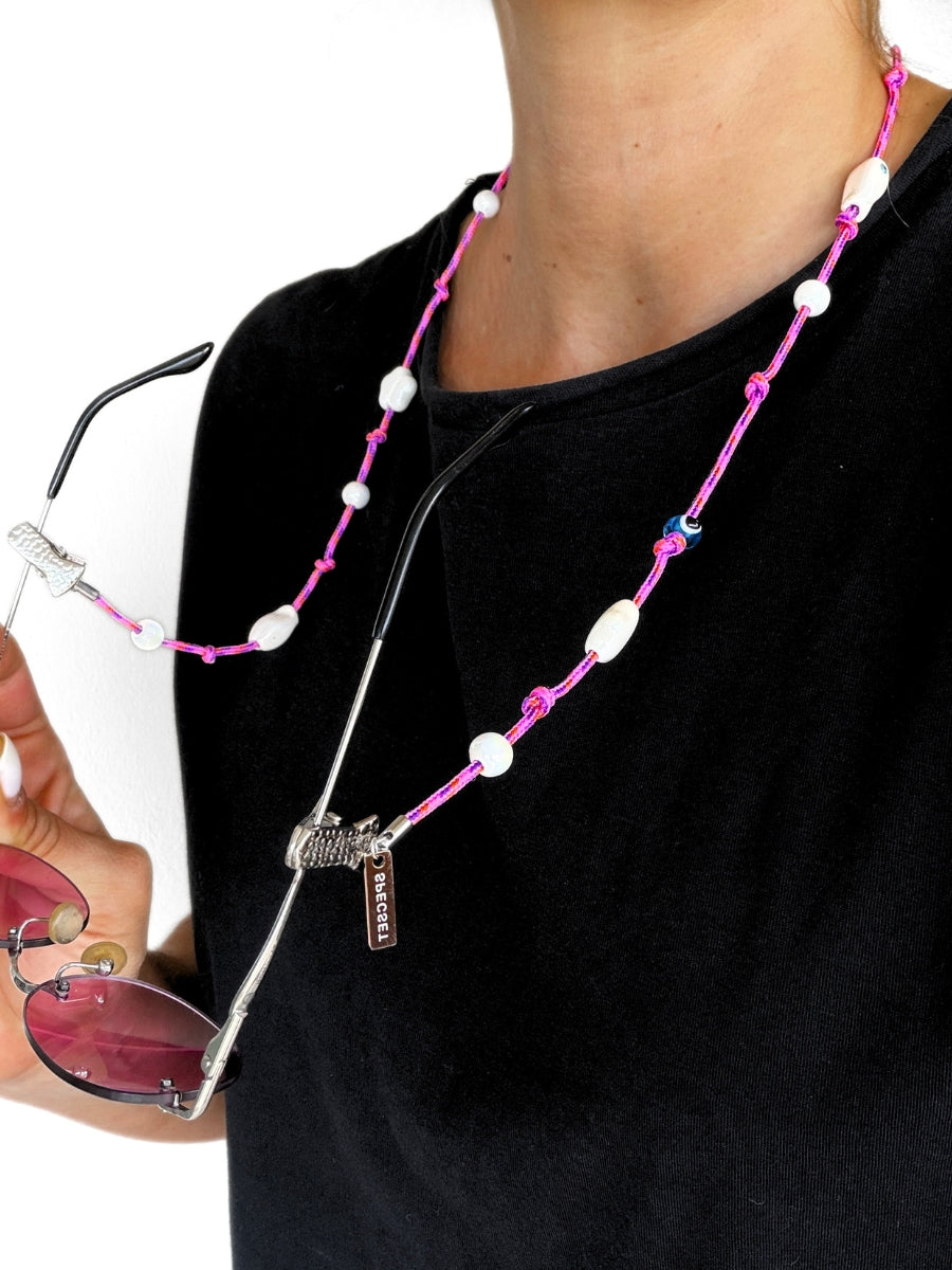 A woman with black outfit wearing the a pink beaded eyewear strap.